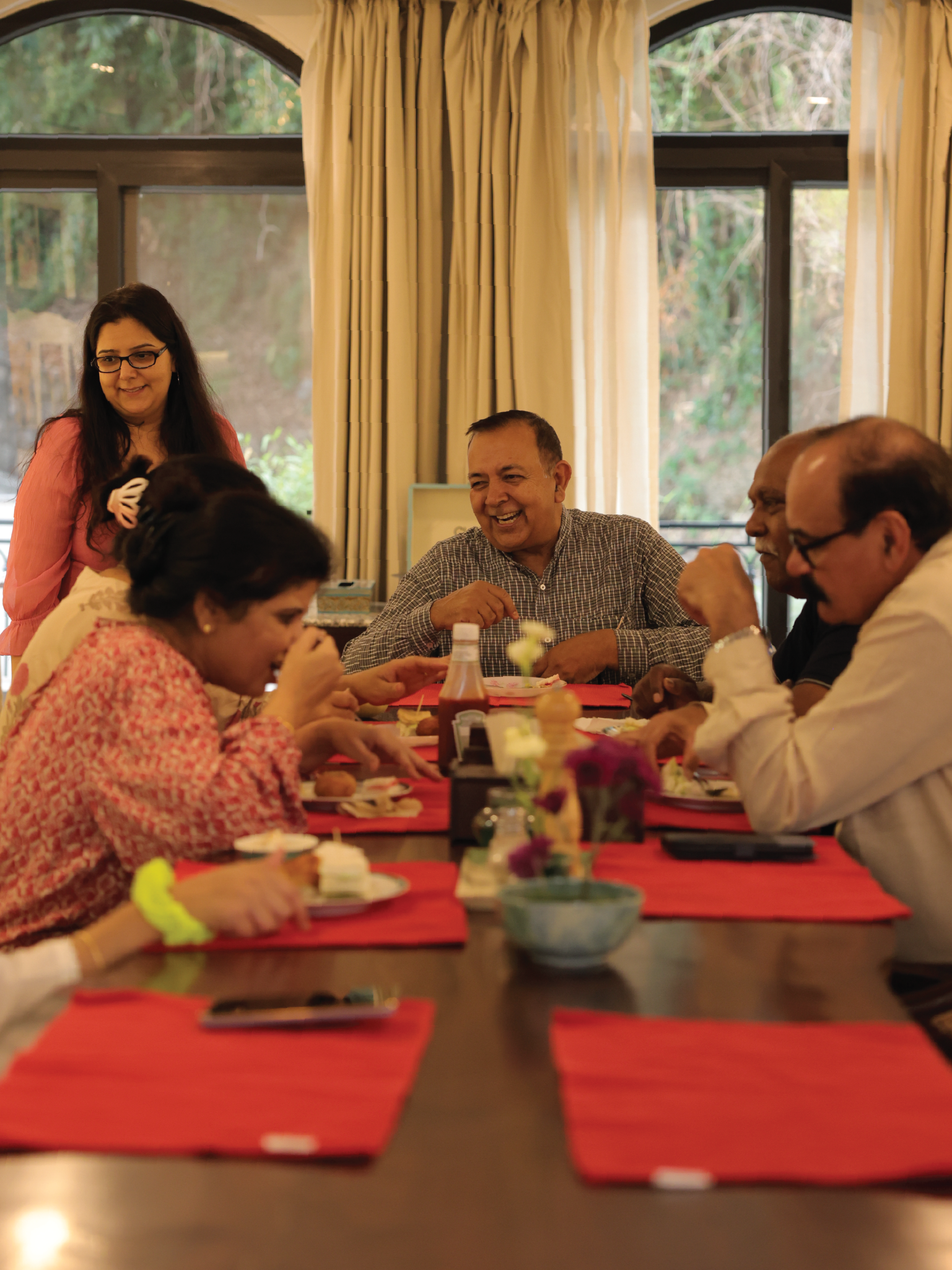 Guests laughing around the long family dining table at Chakk 109